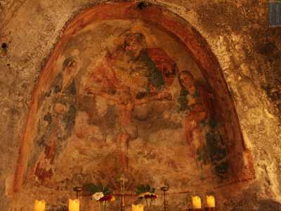 Dalle linee semplici e i colori caldi, l'affresco rappresenta la figura di Cristo crocifisso, su cui il Padre sembra vegliare, assieme allo Spirito Santo sotto forma di colomba
